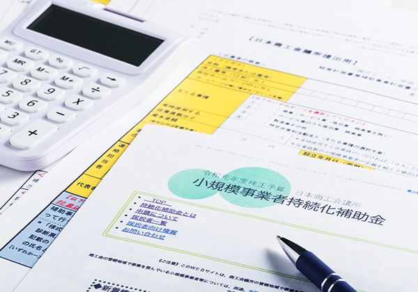 電卓と補助金申請書類で資金計画を検討する様子